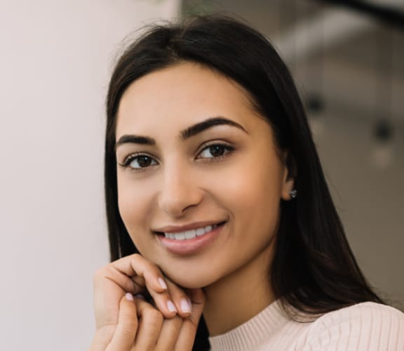 Woman posing with her hands laying against her cheek